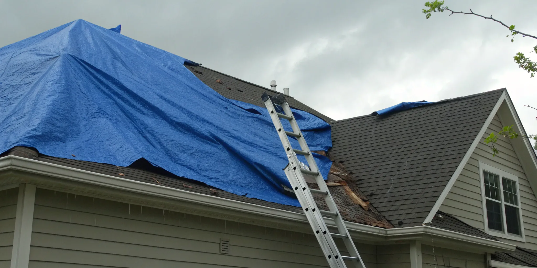 The cost of emergency roof tarping on a storm-damaged home with a blue tarp.