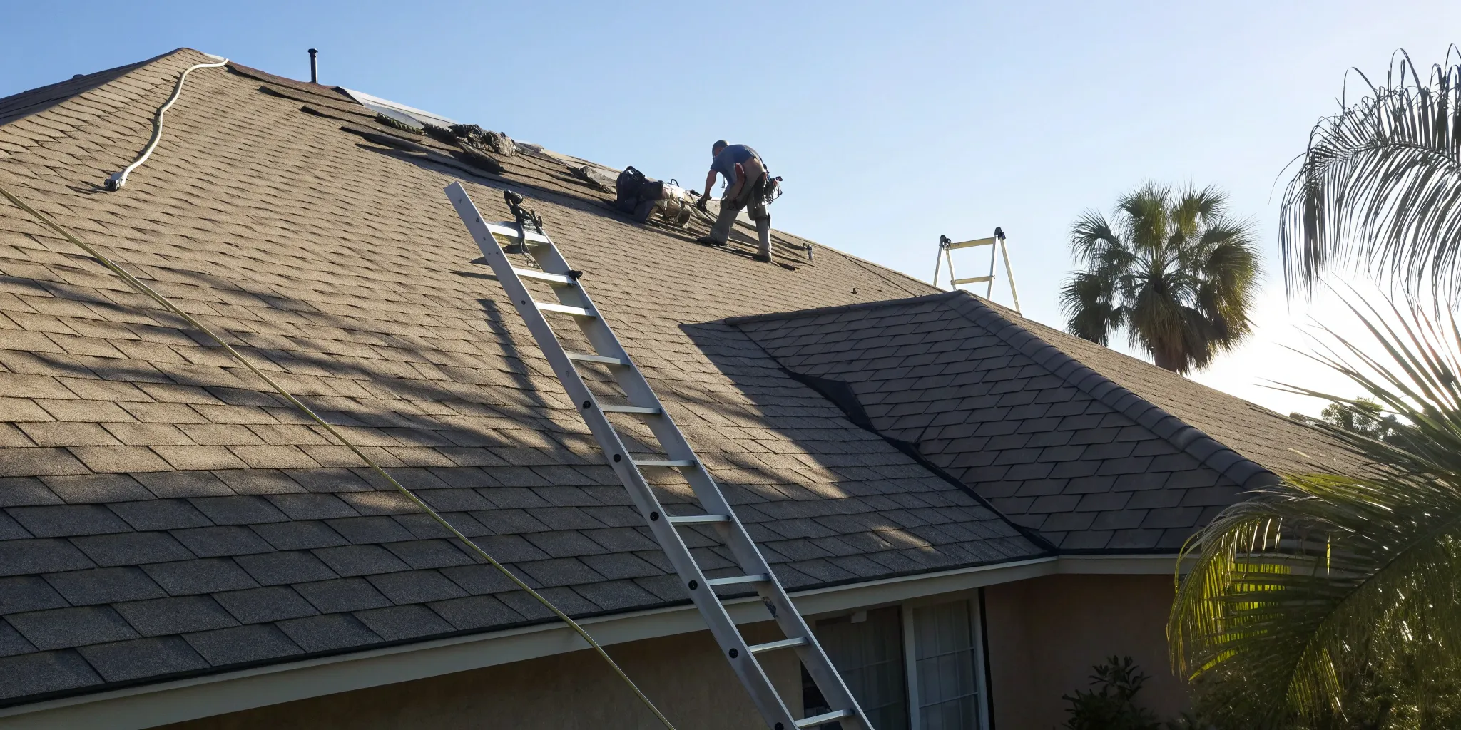 Roofers installing shingles during a roof replacement, a key factor in the average cost.
